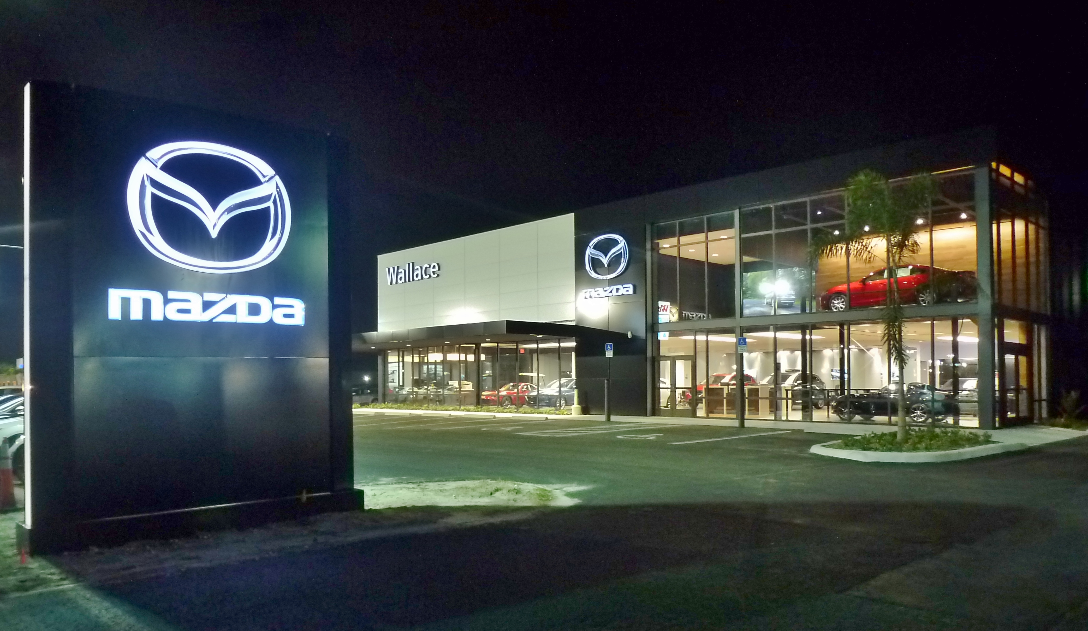 Wallace Mazda Dealership exterior with large glass walls near Palm Beach Gardens, Jupiter, Vero Beach, Palm City, Port Saint Lucie